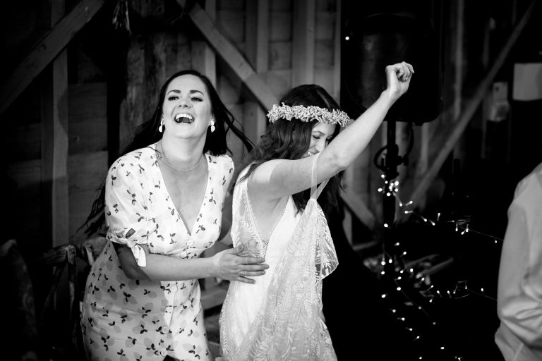 bride and friend dance in a barn