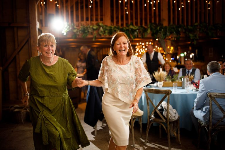 two women dancing inside barn wedding