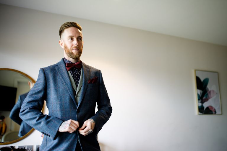 Groom does up suit ready to leave for his wedding ceremony