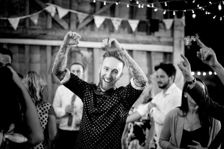 Grooms hands in the air dancing to Mister Kanish at his wedding at The Over Barn