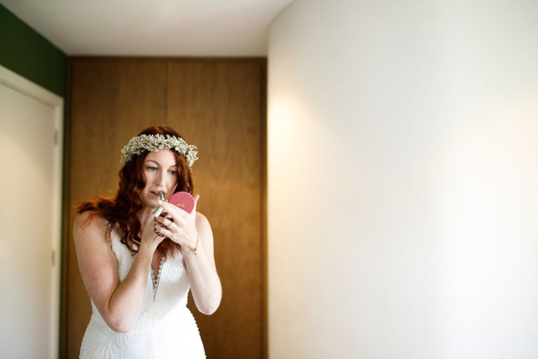 Bride puts on lipstick with her flower crown