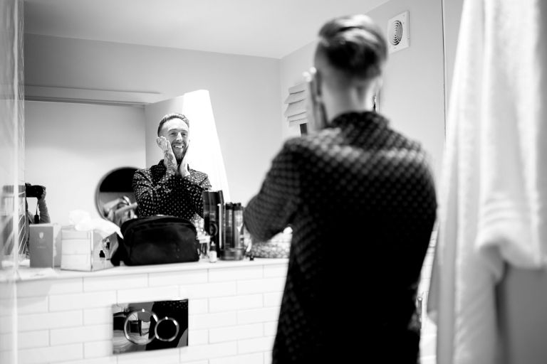 Groom getting ready in a bathroom mirror