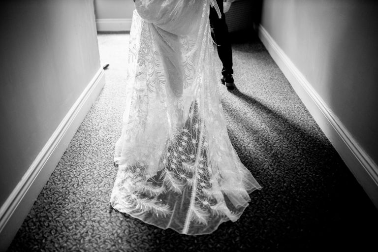 Details of bride's dress and grooms legs as they head to their wedding ceremony at The Over Barn