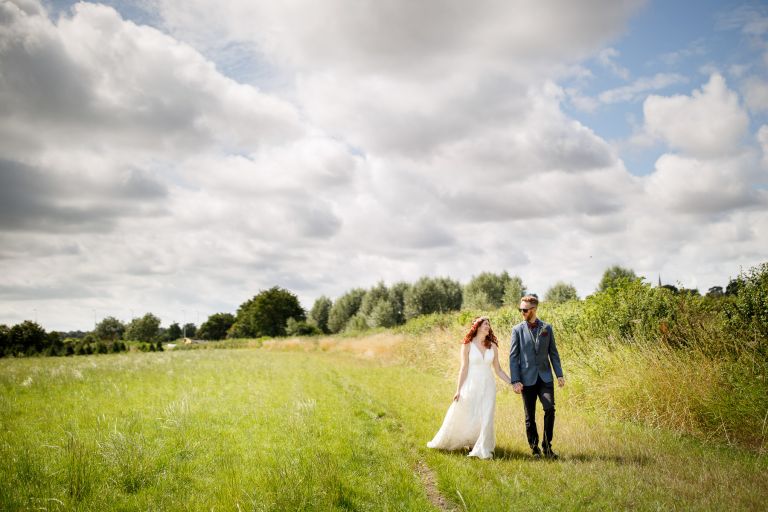 Wedding couple walking in a field in the grounds of The Over Barn