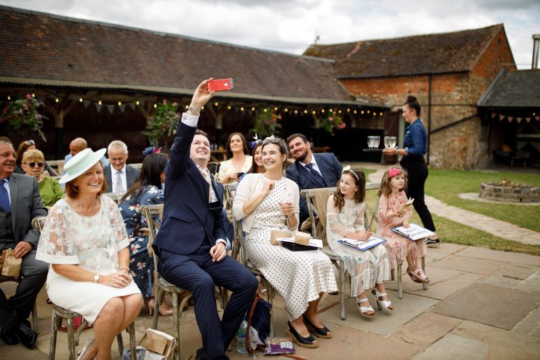 Guests take selfie while waiting for wedding ceremony to start at The Over Barn