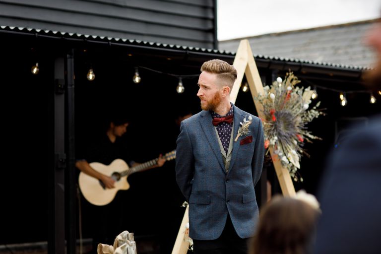 Groom watches bride arrive for their wedding ceremony at The Over Barn