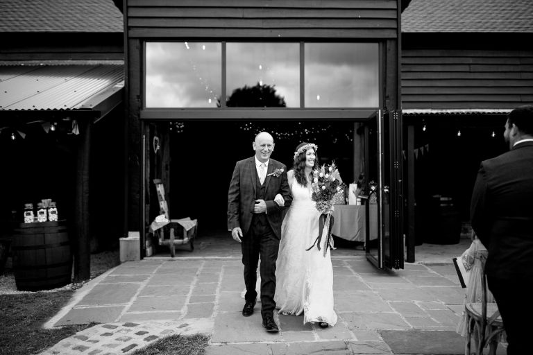 Dad walks bride out to her wedding ceremony from the doors of The Over Barn