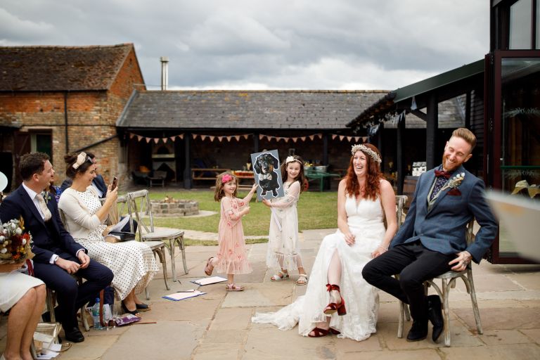 Couple laugh at surprise during their outdoor humanist wedding ceremony at The Over Barn