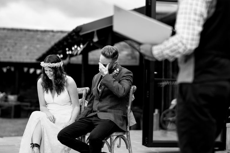 Couple hide face as they laugh during outdoor wedding ceremony at The Over Barn