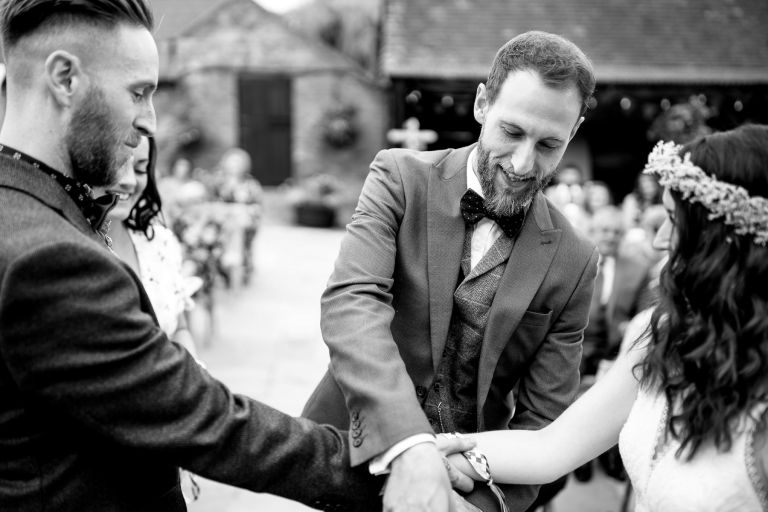 Friend places ribbon for hand fasting during outdoor wedding ceremony in Gloucester
