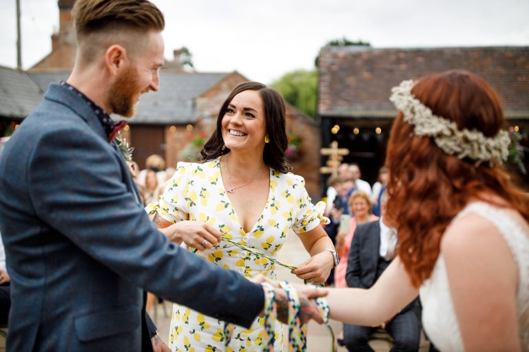 Friend smiles at groom during hand fasting at The Over Barn