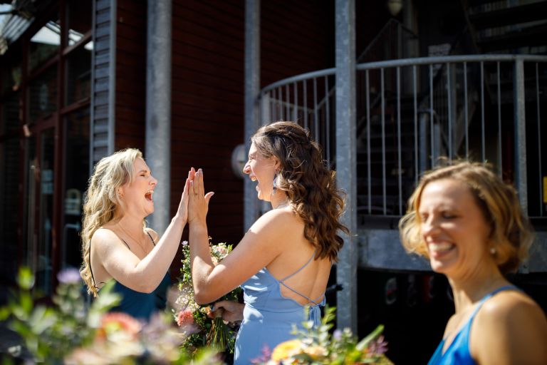 Bridesmaids high five outside the Mud Dock