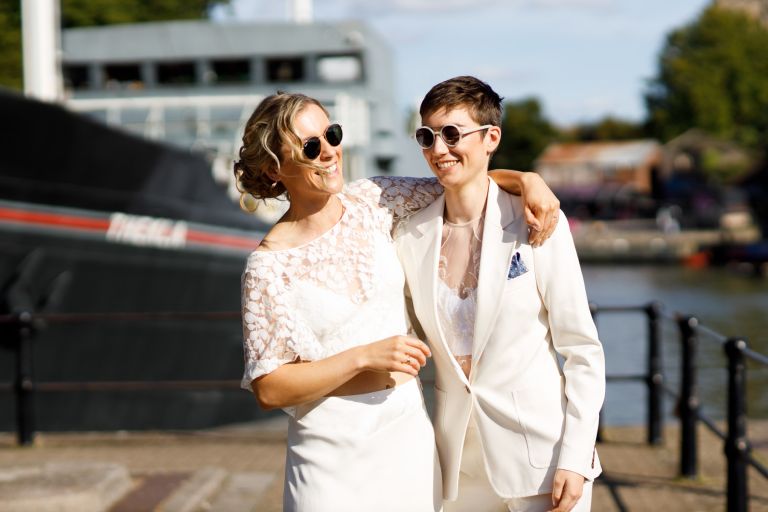 Brides wearing sunglasses laughing in the sun at the The Mud Dock outside Thekla