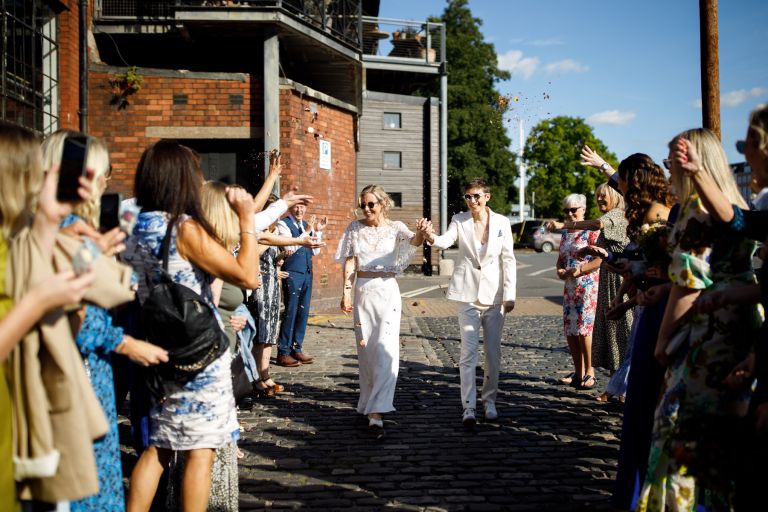 Brides walk through guests throwing confetti at the Mud Dock Bristol