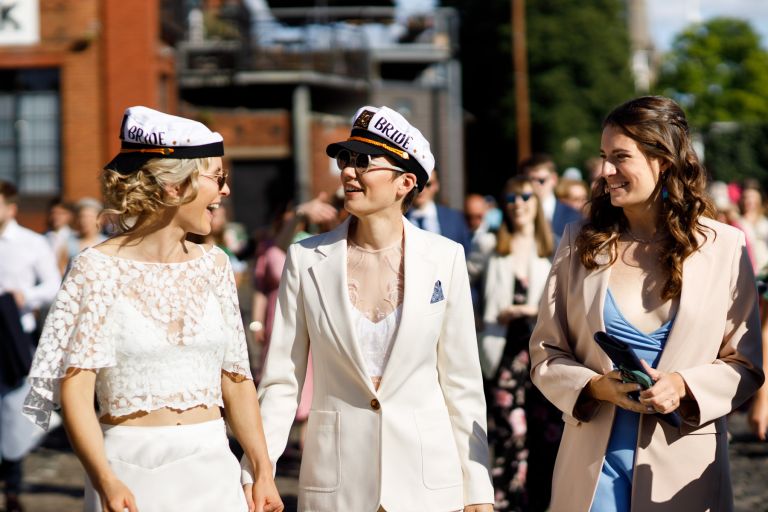 Brides smile at each others wearing hats in city centre Bristol wedding