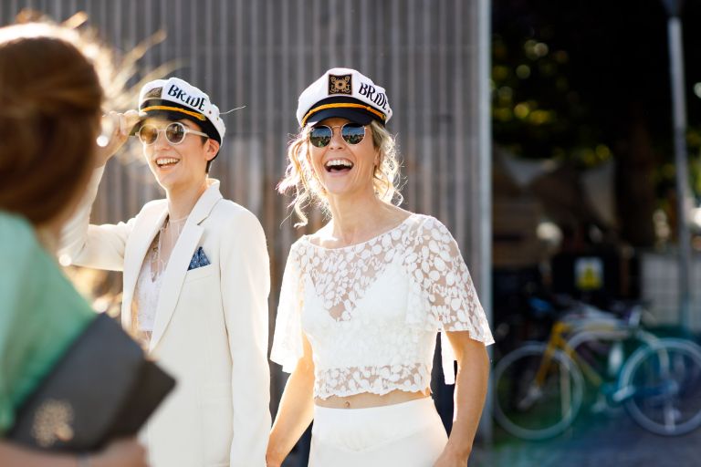 Brides laughing with their captain hats on at city centre Bristol wedding