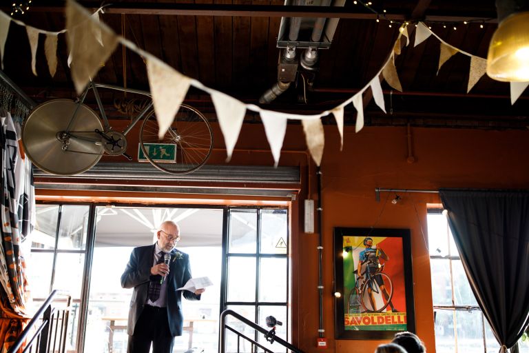 Dad gives wedding speech at the Mud Dock under bunting and bikes