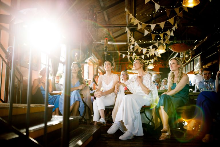 brides listen to wedding speeches at the mud dock same sex Bristol wedding with sunflare