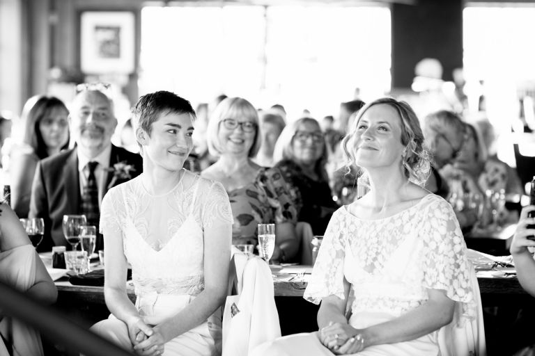 Loving looks from Brides during speeches at same sex Bristol wedding at The Mud Dock