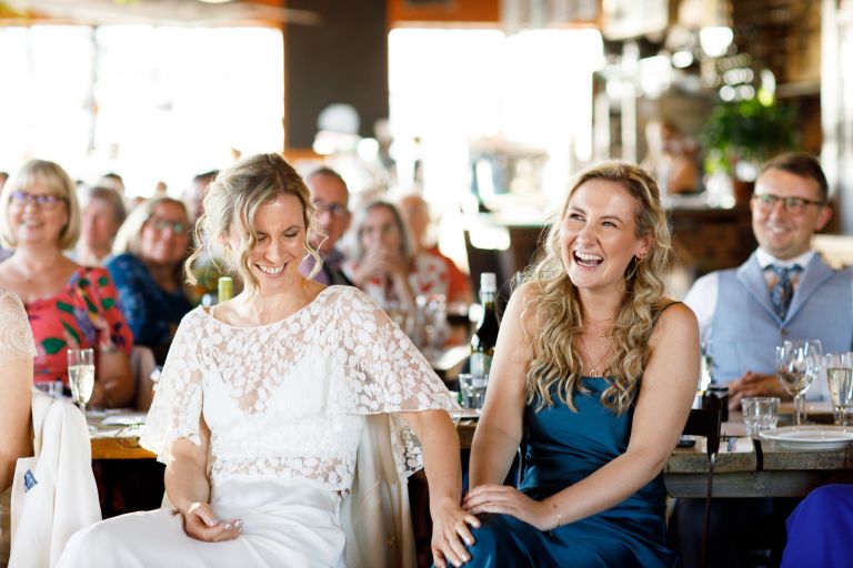 Bride laughs with sister at mud dock wedding